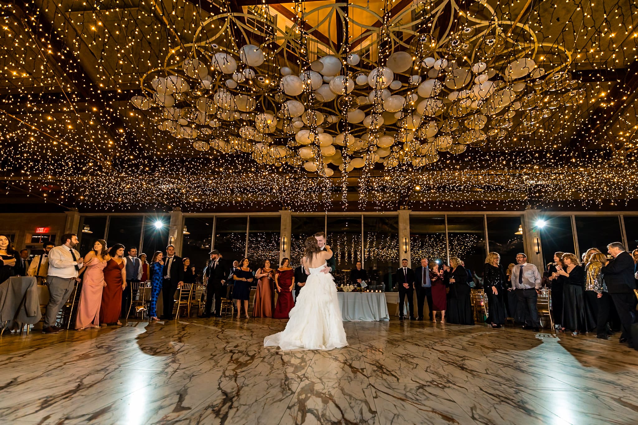 Surrounded by everyone they love, and wrapped in a sea of golden lights, their first dance felt like time stood still. A dreamy beginning to a lifetime of twirls, laughter, and love.