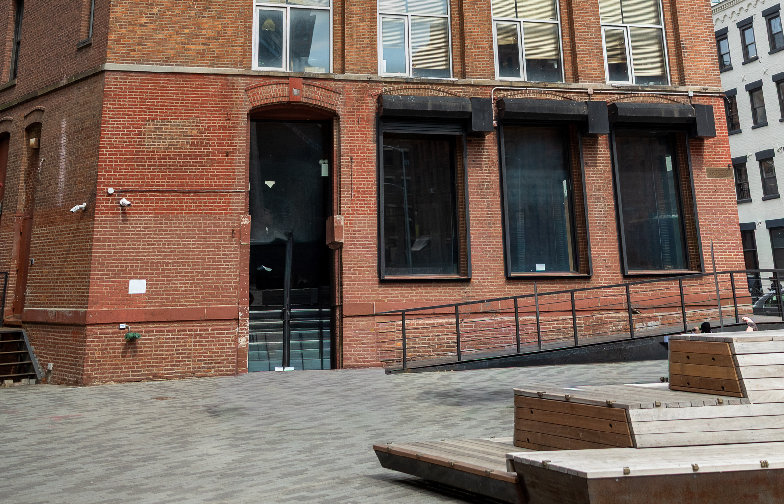 Exterior of DUMBO Loft in Brooklyn featuring red brick facade, industrial windows, and minimalist urban courtyard.