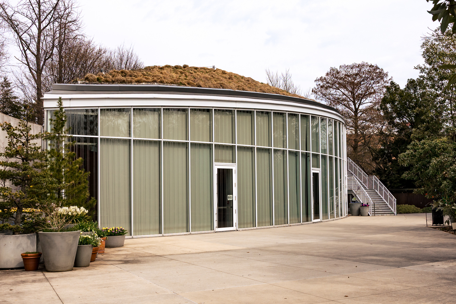 Brooklyn Botanic Garden Atrium exterior with curved glass walls, minimalist design, and surrounding greenery.