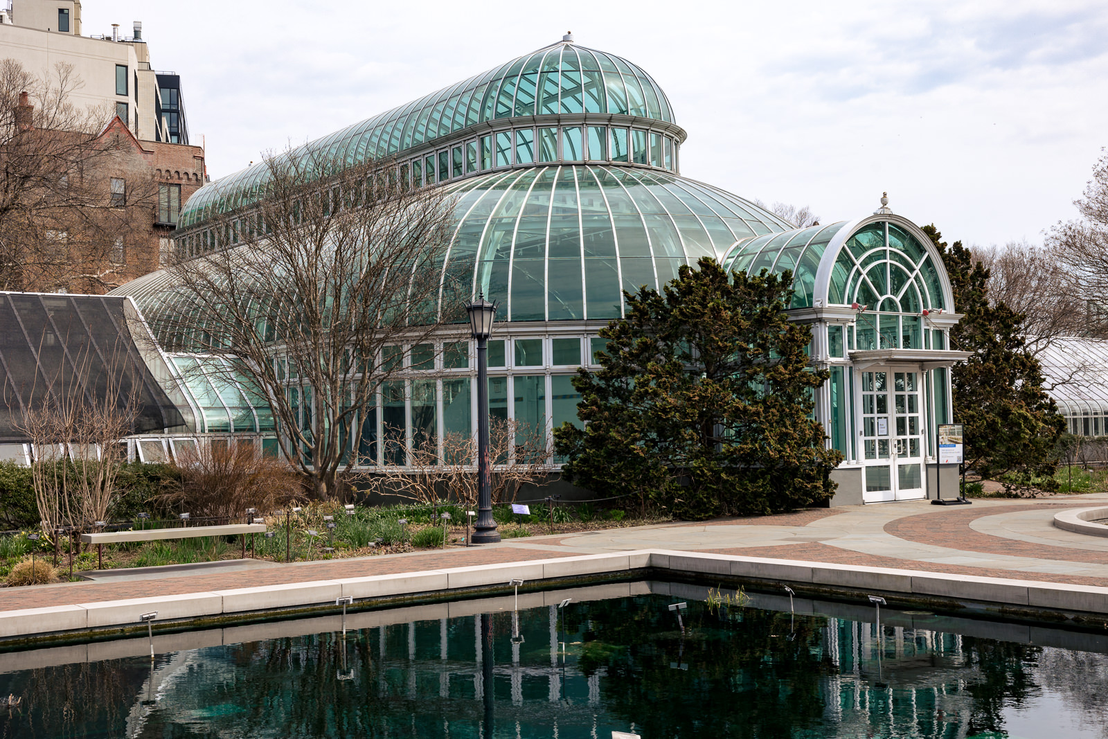 Palm House at Brooklyn Botanic Garden showcasing its grand glass dome and serene water reflection.