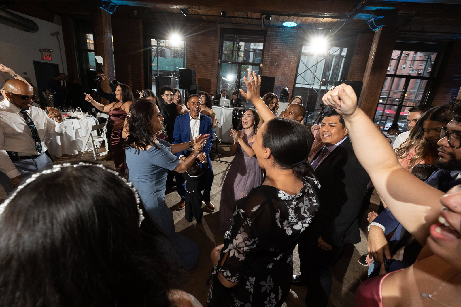 Wedding guests dancing at DUMBO Loft with lively energy, warm lighting, and an industrial brick interior.