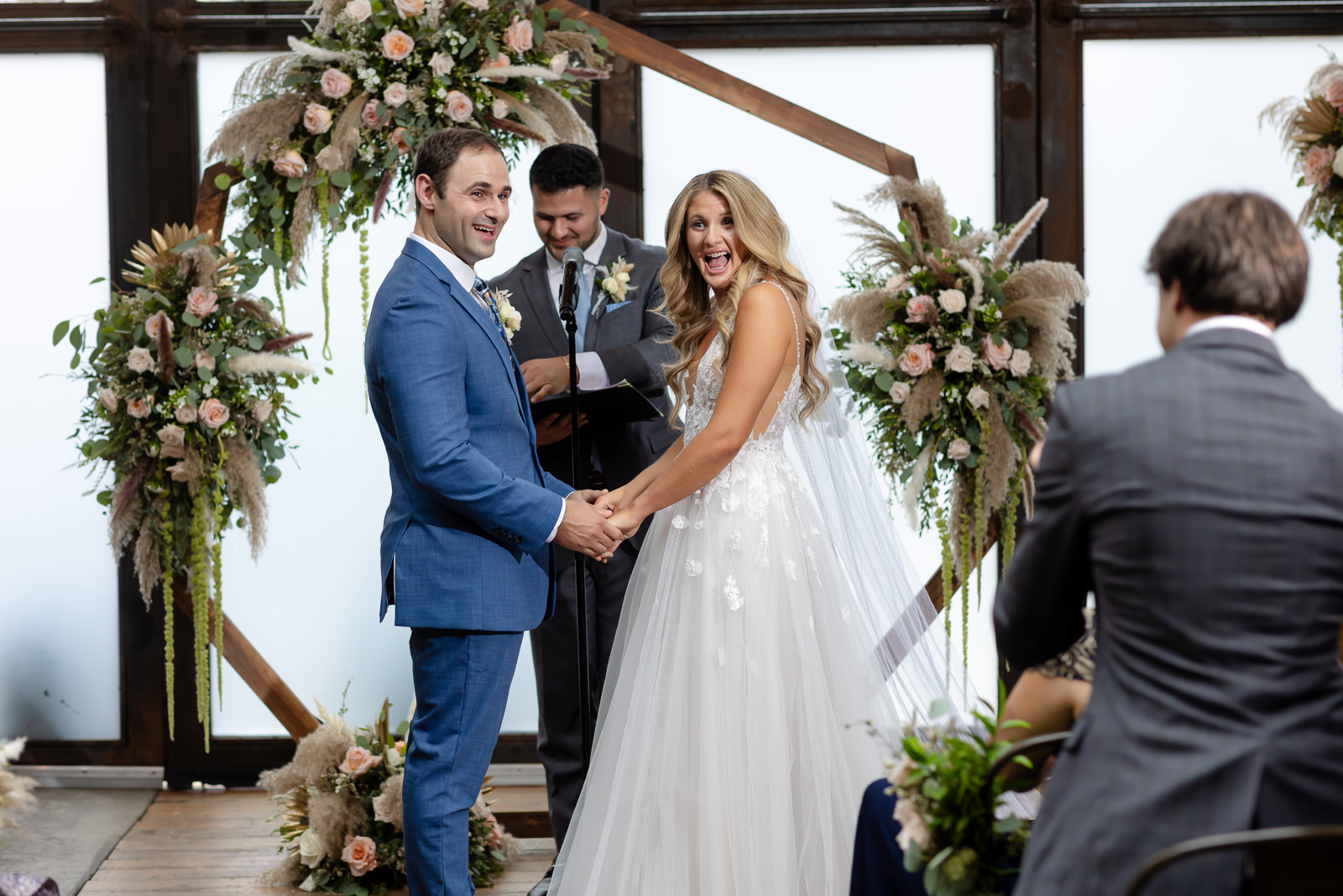Paola and Alex smiling during their wedding ceremony at Brooklyn Winery.