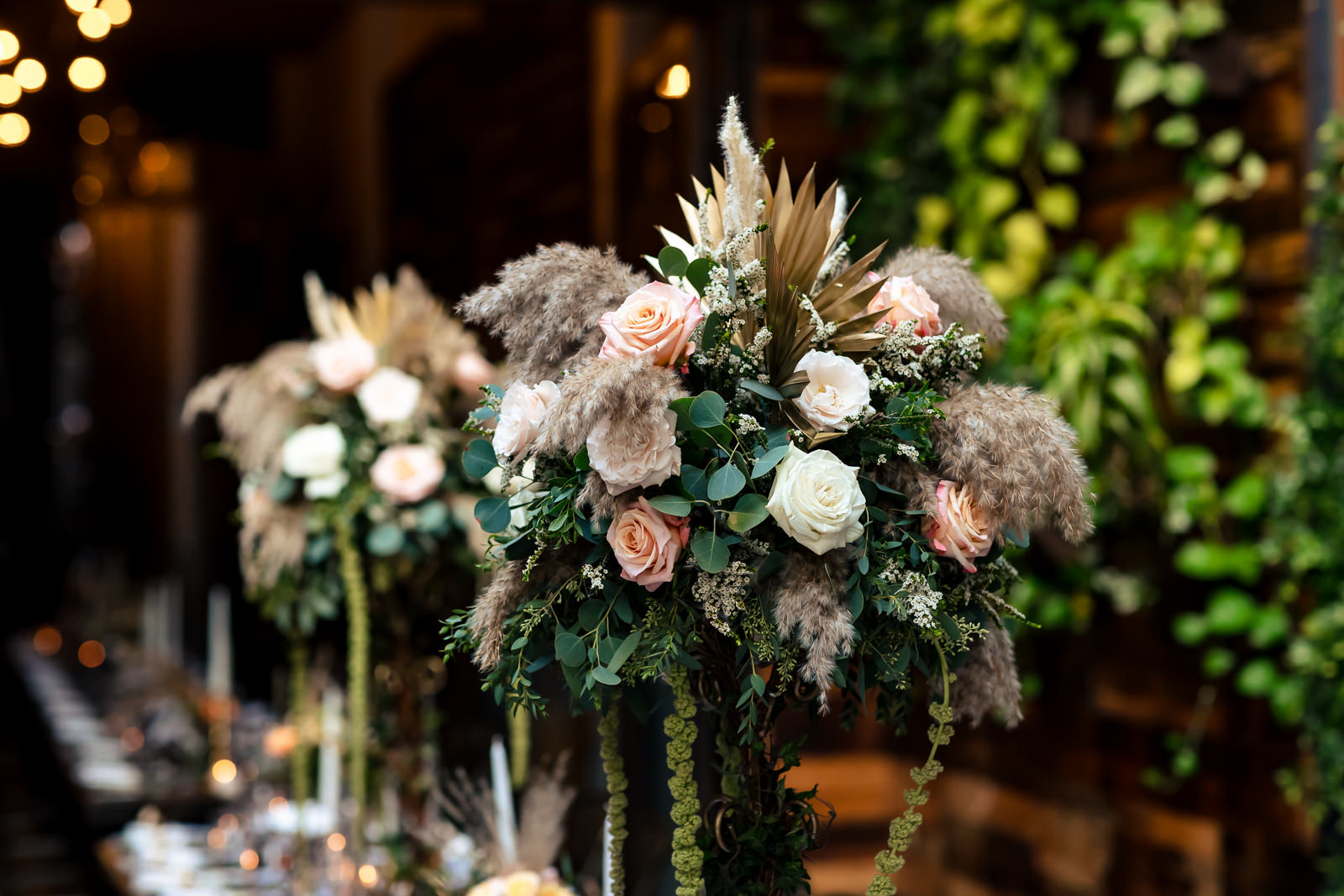 Reception centerpiece featuring blush florals, greenery, and candlelight.