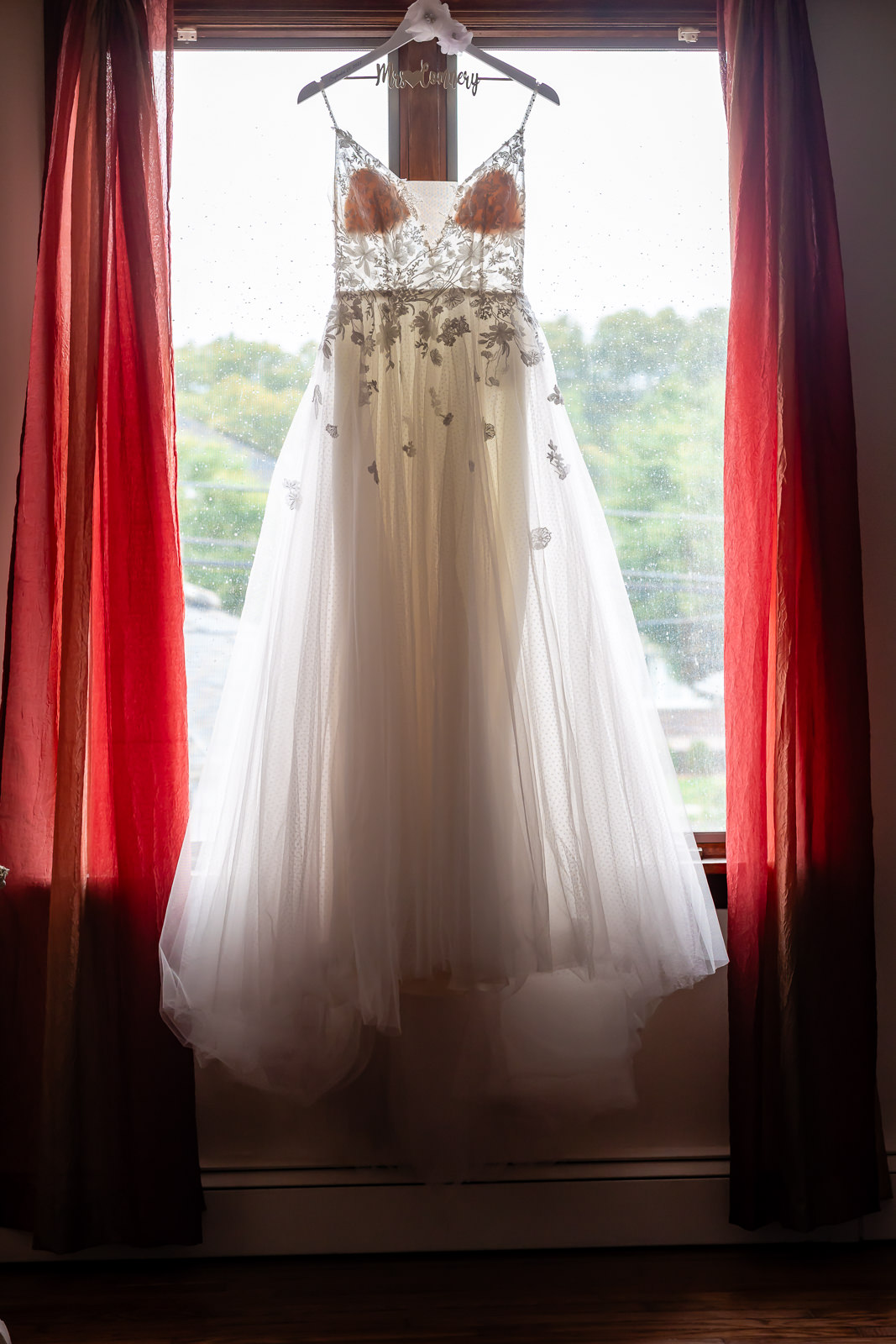Wedding dress hanging in front of a window before a Brooklyn Winery wedding.