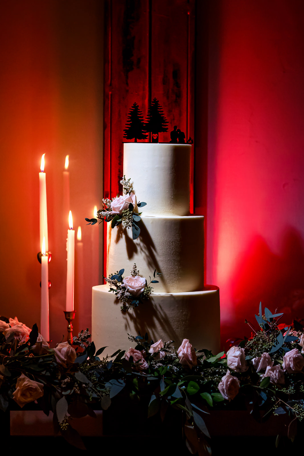 Wedding cake displayed with candles and floral accents at Brooklyn Winery reception.